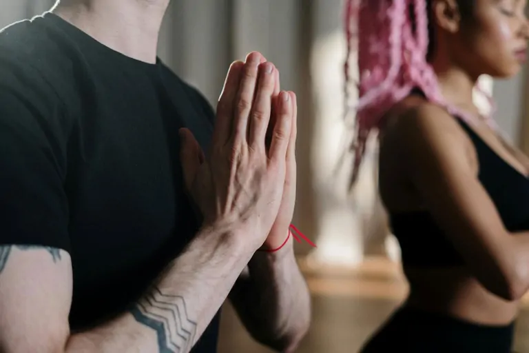 A close-up of two people in a yoga pose, at Suniai Oliva as they practice mindfulness together.