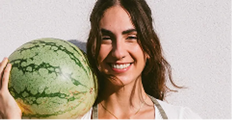 Laia smiles while holding a large watermelon, captured during the Wild Medicine Workshop at Suniai Oliva.