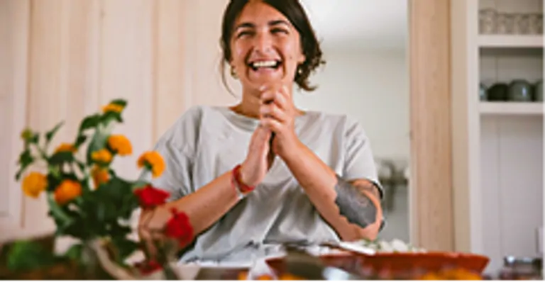 Natalia smiles joyfully at a table adorned with flowers and delicious dishes, capturing a warm, inviting moment.