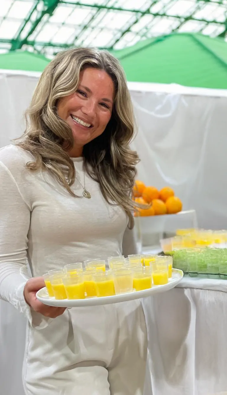 Malou, responsible for vision & aesthetics at Suniai Oliva, presents fresh oranges drinks at the event.