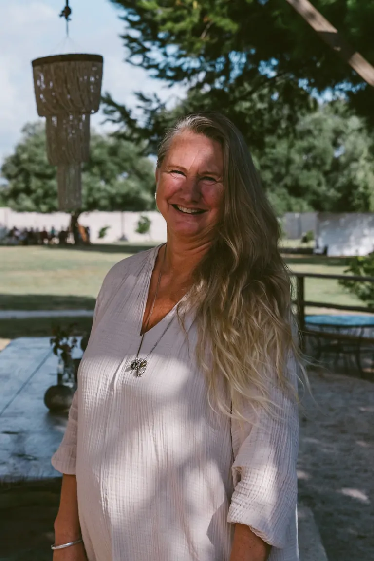 Marie, Co-founder of Suniai Oliva, smiles warmly amidst a lush outdoor setting.