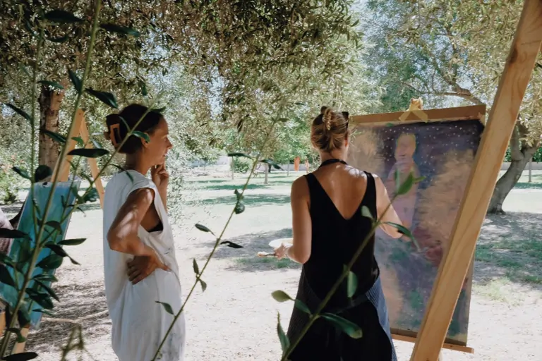 Two women admire art at Suniai Oliva Retreat Center in Spain, surrounded by nature, embodying the essence of peaceful retreats.