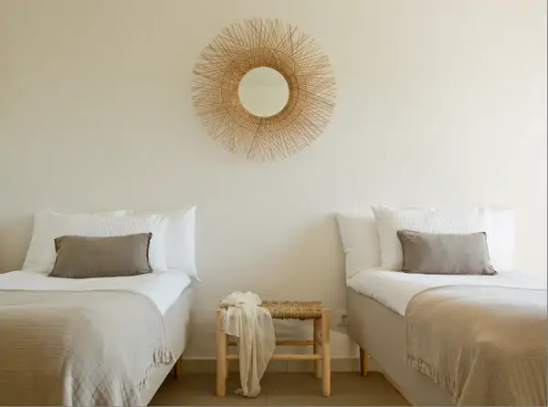 Bright and serene Rooms at Suniai Oliva Retreat Center in Spain feature two single beds and a decorative mirror.