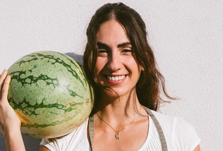 Laia smiles while holding a large watermelon, captured during the Wild Medicine Workshop at Suniai Oliva.