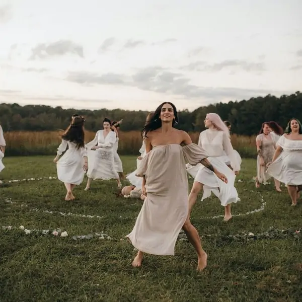 A joyful participant runs in a circle with others at the VÍVETE Retreat in Suniai Oliva, surrounded by nature.