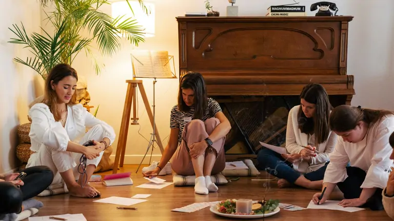 A yoga class in session at the Suniai Oliva Retreat Center, with participants stretching in a bright, airy studio.