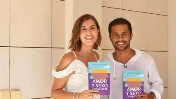 Two smiling individuals hold up books titled 
