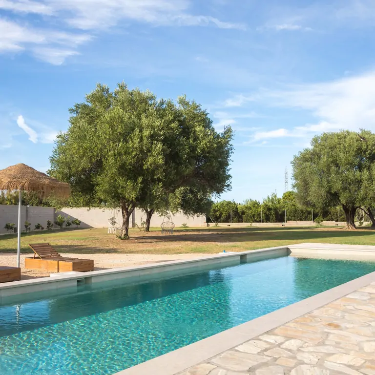A serene view of Suniai Oliva Retreat Center features a tranquil pool surrounded by lush greenery and inviting lounge chairs.