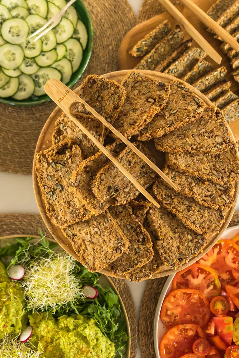A vibrant spread of assorted salads, cucumber slices, and crackers in bowls, displayed on woven placemats.