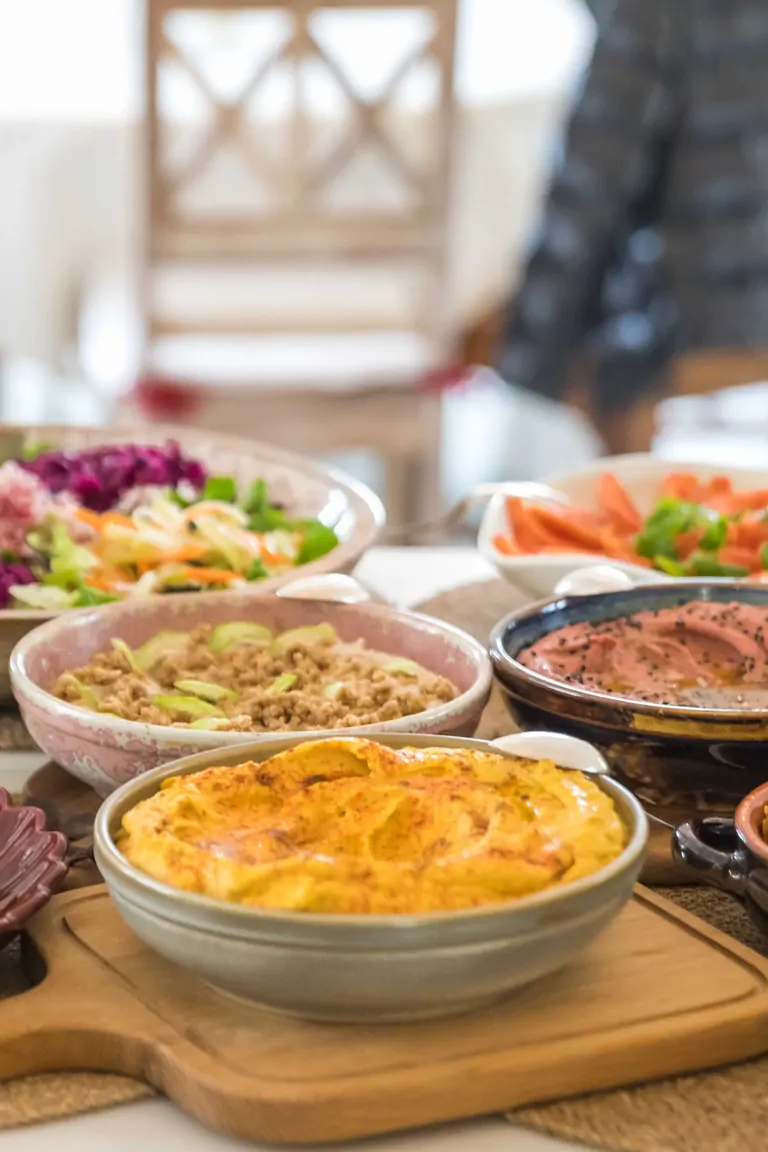 A colorful spread of dishes laid out on a table at Suniai Oliva Center, featuring salads, casseroles, and appetizers.
