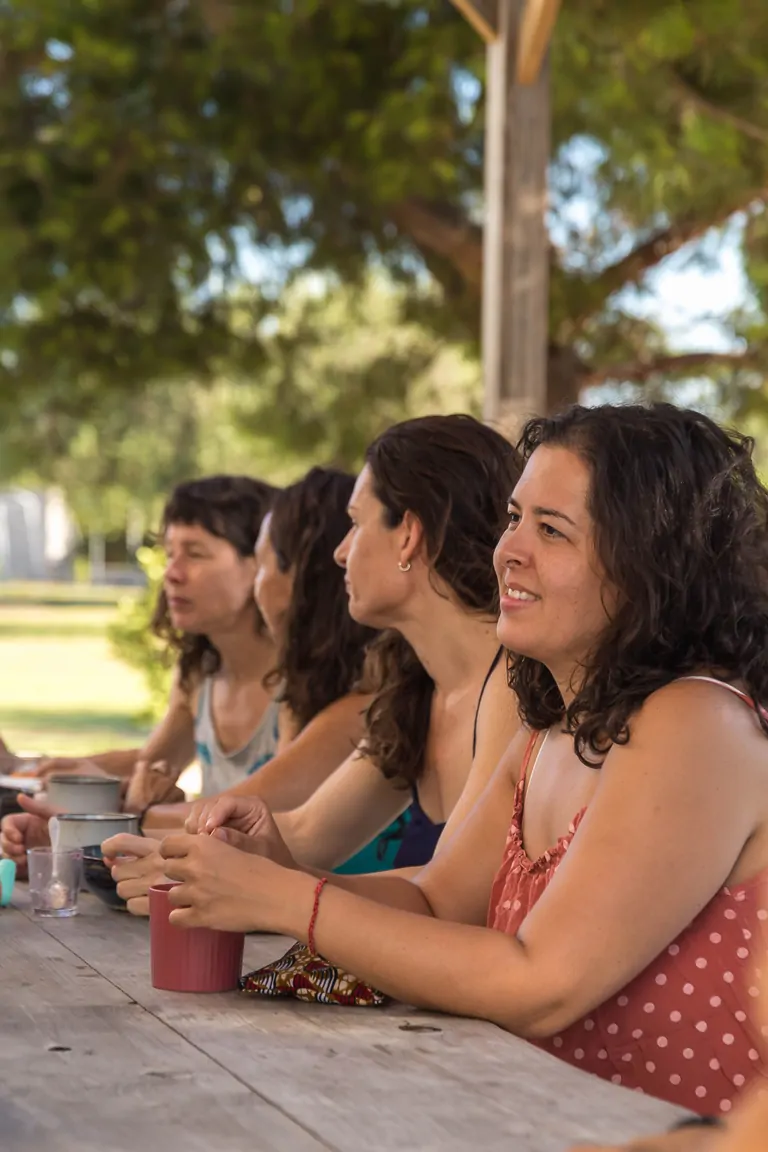 A group enjoys a relaxed meal at Suniai Oliva Retreat Center, surrounded by nature and vibrant conversation.