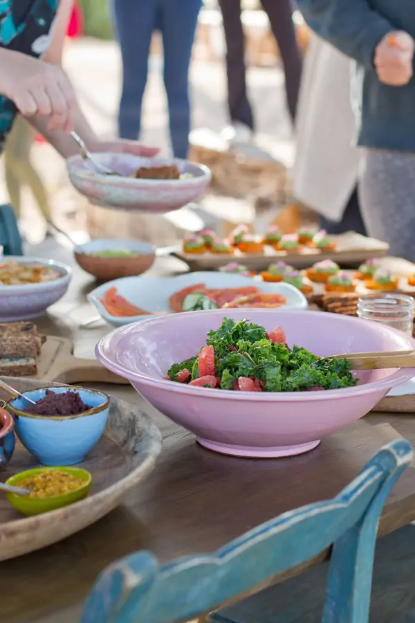 A vibrant gathering of people enjoying a meal, featuring fresh dishes at Suniai Oliva Retreat Center's communal table.