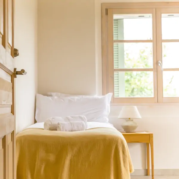 A serene window with green shutters, framed by a flower pot, evokes tranquility at Suniai Oliva by the Beach, a Yoga Retreat in Spain.